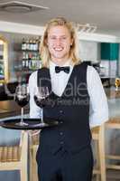 Portrait of waiter holding tray with glasses of red wine