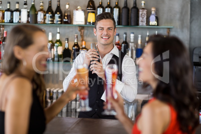 Two women having cocktail while a waiter preparing cocktail with