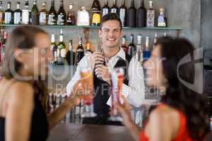 Two women having cocktail while a waiter preparing cocktail with