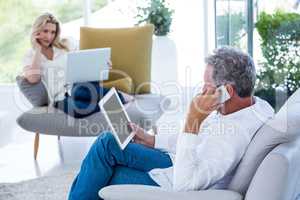 Man talking on phone while holding tablet with woman