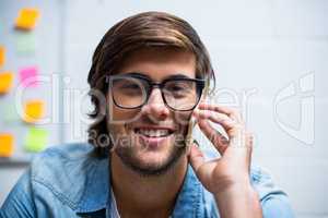 Portrait of smiling man talking on phone in office