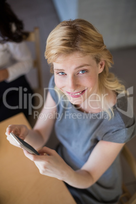 Beautiful woman sitting on table and using mobile phone