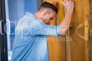 Tensed young  man leaning on door