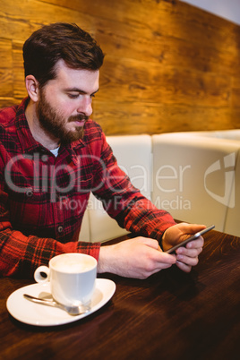 Man using mobile phone by coffee cup in restaurant