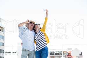 Happy mature couple taking selfie in city