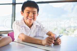 Schoolkid using mobile phone in classroom