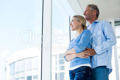 Couple looking through window at home