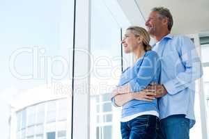 Couple looking through window at home
