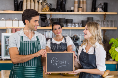 Smiling colleagues showing chalkboard with open sign