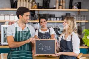 Smiling colleagues showing chalkboard with open sign