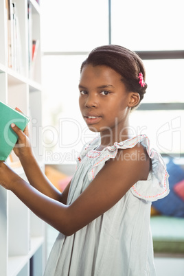 Girl taking a book from bookshelf in library