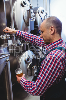 Manufacturer filling beer from storage tank at distillery