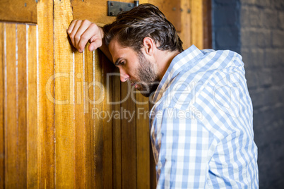 Depressed man leaning on door