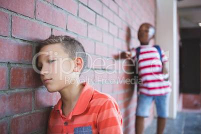 Schoolkid bullying a sad boy in corridor