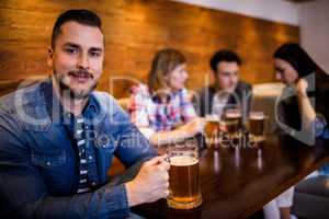 Man holding beer mug while friends in background