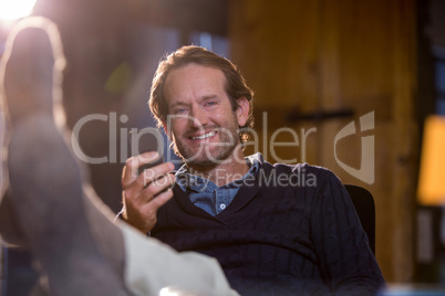 Smiling businessman holding cellphone in office