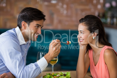 Smiling man feeding meal to woman