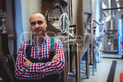 Manufacturer with arms crossed standing at brewery