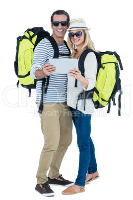 Cheerful couple with luggage and digital tablet