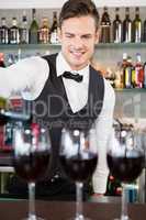 Waiter pouring wine into glasses