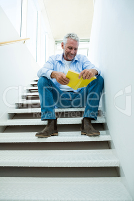 Smiling man reading book on steps