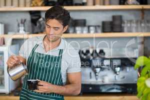 Smiling waiter pouring a cup of coffee