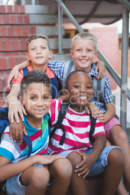 Smiling schoolkids sitting on staircase at school