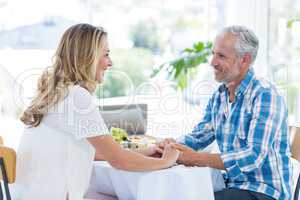 Mature couple holding hands in restaurant