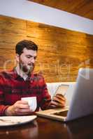 Man using mobile phone by laptop in restaurant