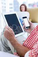 Midsection of man holding tablet and phone