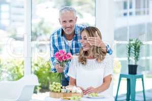 Mature man giving pink roses to wife in restaurant