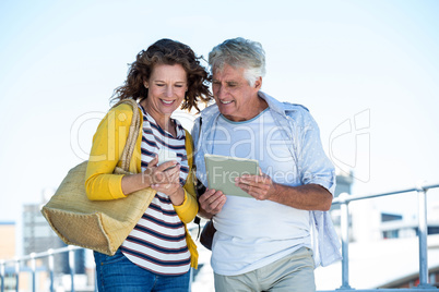 Happy couple using digital tablet and mobile phone