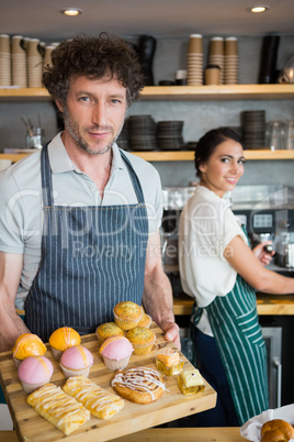 Waiter holding wooden tray with dessert