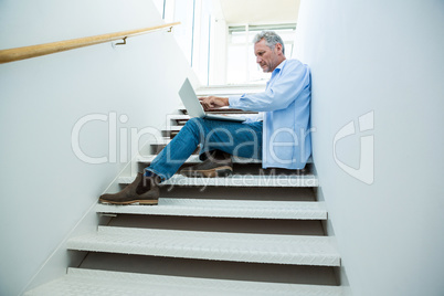 Focused man using laptop on steps