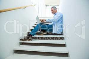 Focused man using laptop on steps