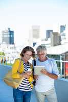 Couple using digital tablet and mobile phone on walkway