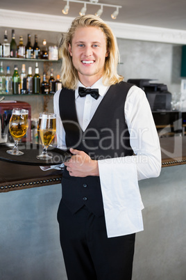 Portrait of waiter holding tray with glasses of beer