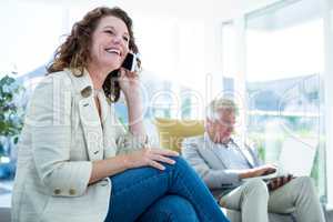 Smiling woman by man talking on mobile phone