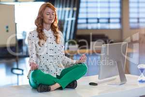 Businesswoman doing yoga in office