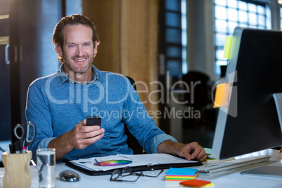 Businessman with cellphone at computer desk