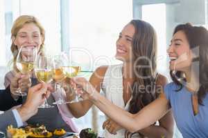Happy female colleagues toasting beer glasses while having lunch