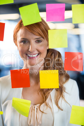 Businesswoman seen through glass with adhesive notes