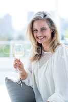 Smiling woman holding wineglass at home