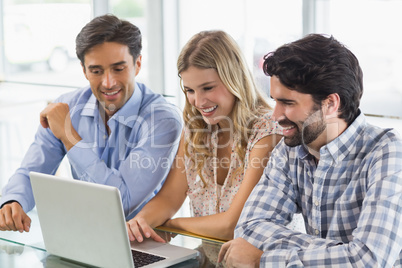 Smiling woman and two men using laptop