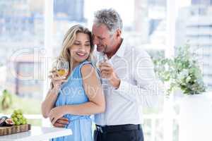 Romantic mature couple holding white wine at restaurant