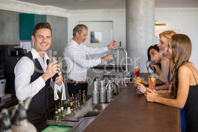 Beautiful women having cocktail while waiter preparing cocktail