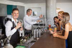 Beautiful women having cocktail while waiter preparing cocktail