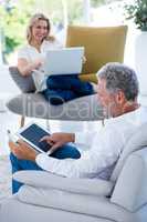 Mature man using tablet while woman holding laptop