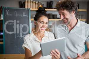 Waiter and waitress discussing over digital tablet