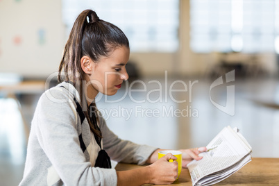 Woman reading newspaper in office